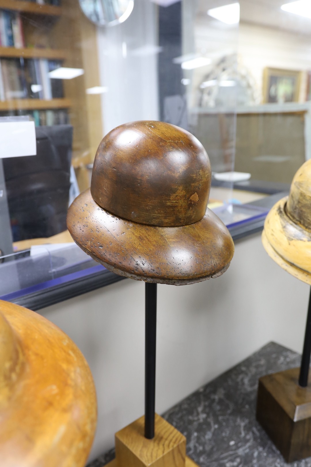 A group of three vintage milliner's hat-blocks, on stands
